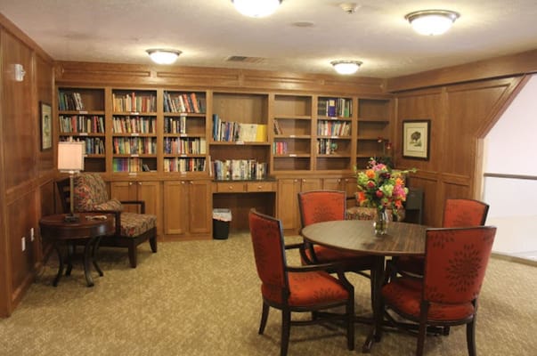 A reading area with a table, chairs, and bookshelves filled with books.