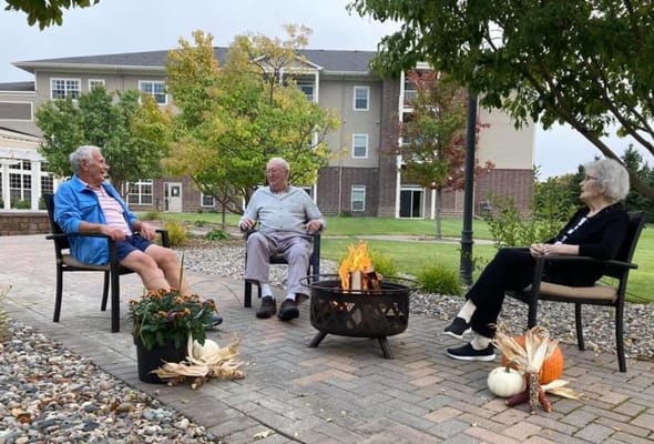 Three senior residents sitting around a bonfire in the courtyard.