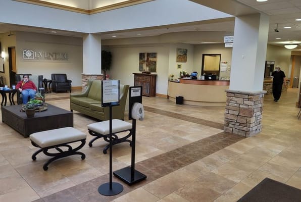 Lobby area with seating and a reception desk at Sheyenne Crossings Senior Living Apartments.