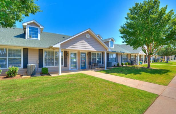 Sunlit exterior of Silver Elm Estates with green lawn and pathways.