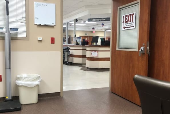 View of the registration area, showing sign for 'Your Nurse' and a visible exit sign.