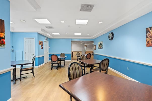 Bright dining area with wooden tables and chairs in a senior living facility.