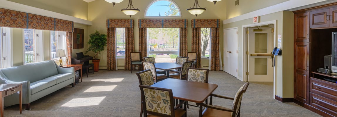 Bright lounge area with sofas and tables in St. Teresa Rehabilitation and Nursing Center
