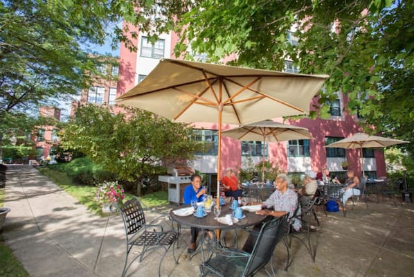 Residents seated at tables under umbrellas on the patio