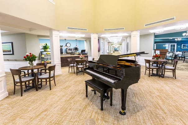 A grand piano in the common area with seating and floral arrangements.