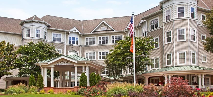 Entrance of Sunrise at Buckhead senior living facility with flag and greenery