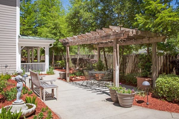 Serene outdoor garden with a pergola, seating, and landscape plants.