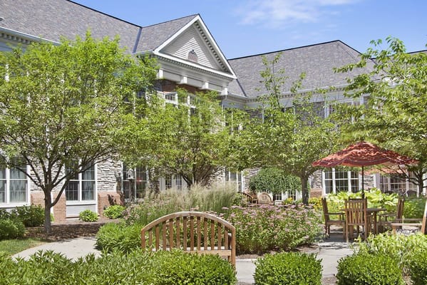 Lush garden area with benches and patio seating at Sunrise of Grosse Pointe Woods