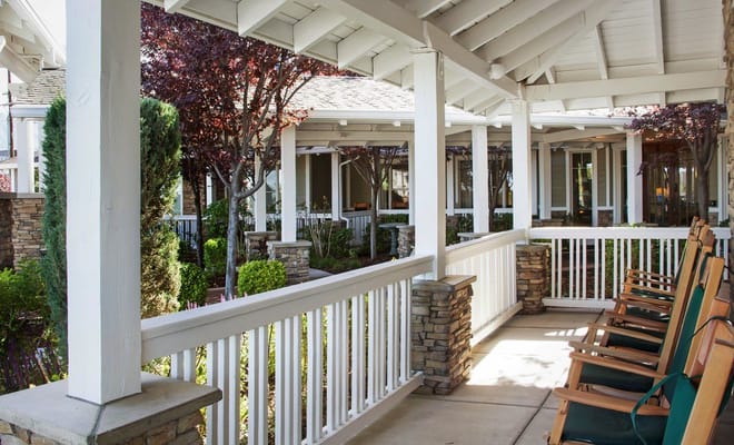 View of the porch area with rocking chairs and garden landscaping.