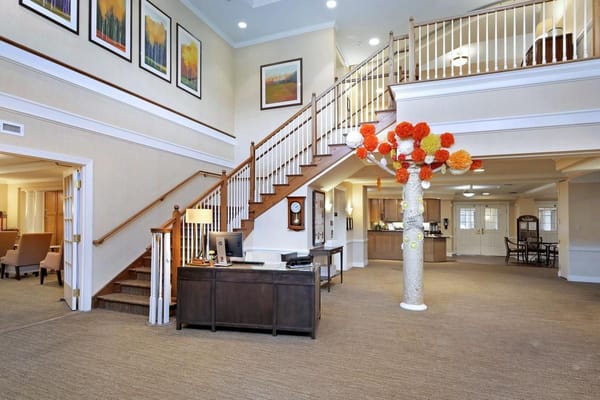 Spacious lobby area with staircase and decorative tree