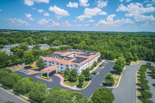 Aerial view of The Charlotte Assisted Living & Memory Care facility surrounded by trees.