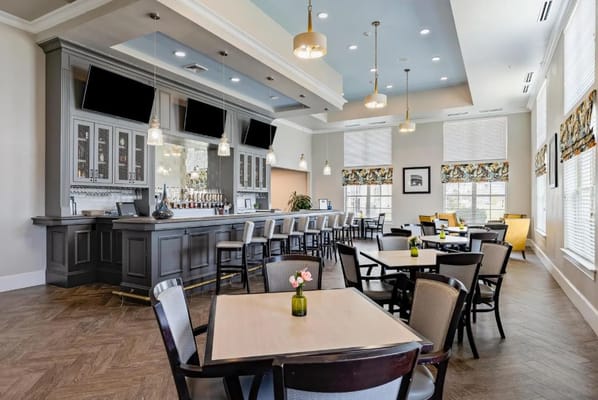 Elegant bar area with tables and seating in a senior living facility.