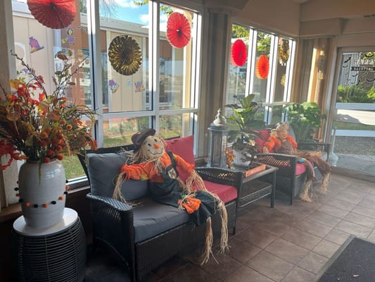 Cozy lobby area decorated for fall with scarecrows and plants