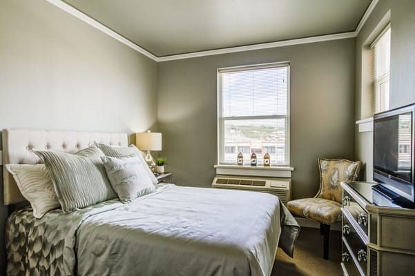 Well-furnished bedroom with a bed, lamp, and TV