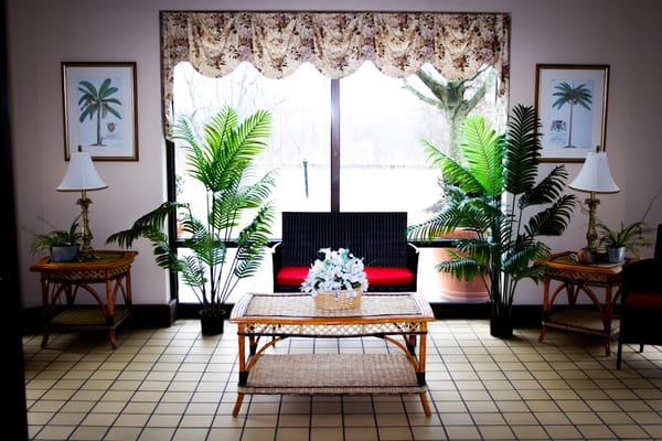 A welcoming lobby with palm plants and a seating area at The Residence at Arrowood.