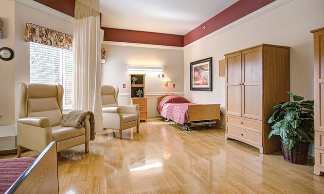 A comfortable bedroom with two chairs, a bed, and wooden furniture.