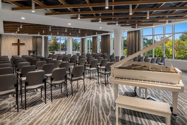 Bright interior of a community room with seating and a piano