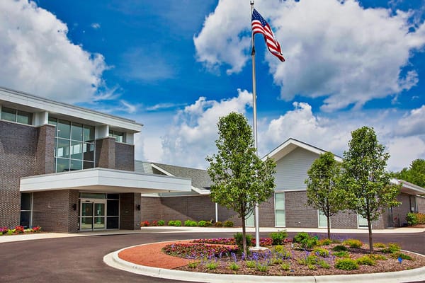 Modern front entrance of Thrive of Fox Valley senior living facility with landscaped gardens.