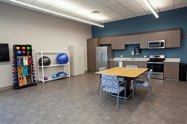 Bright and spacious activity room with fitness equipment and a kitchenette