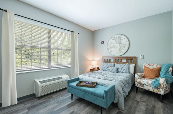 A cozy bedroom with a bed, chair, and window