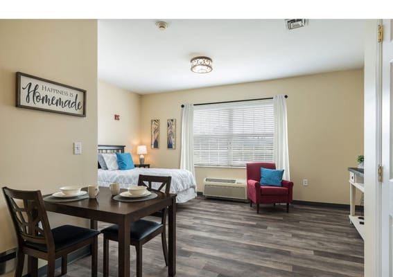 A cozy resident room featuring a bed, dining table, and seating area.