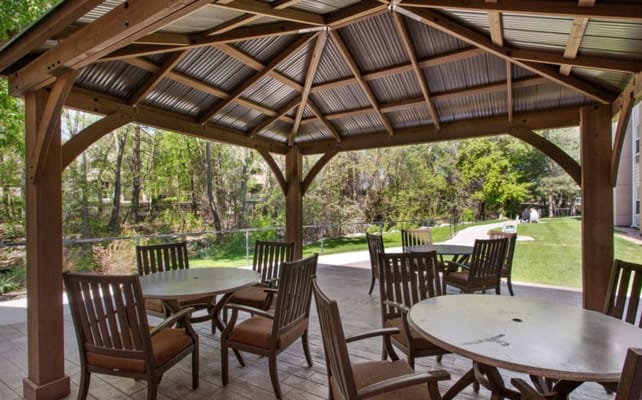 Wooden gazebo with tables and chairs overlooking landscaped grounds