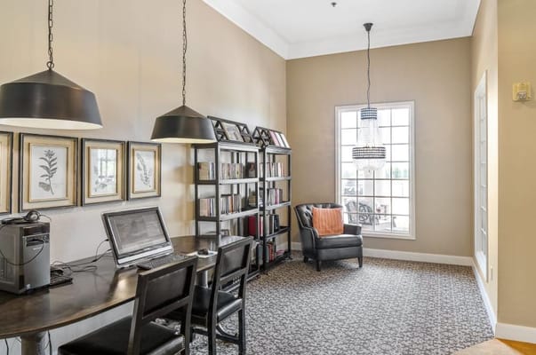 A library corner with a desk, black chairs, and bookshelves in Villagio of Oklahoma City.