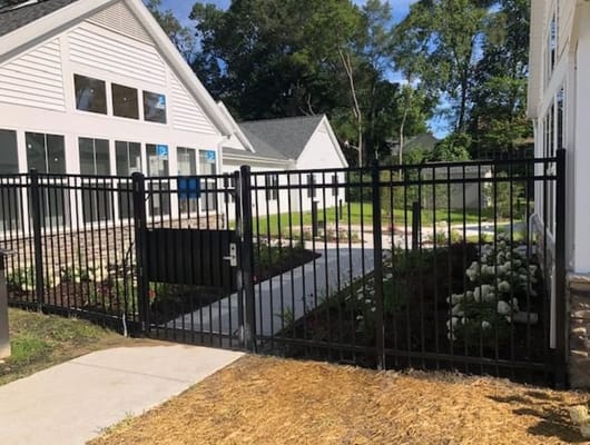 Black gate leading to a landscaped pathway at Willow Creek West AFC