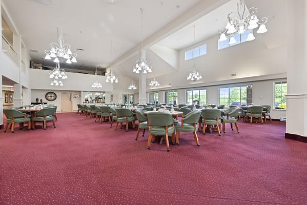 Spacious dining area with chandeliers and green chairs