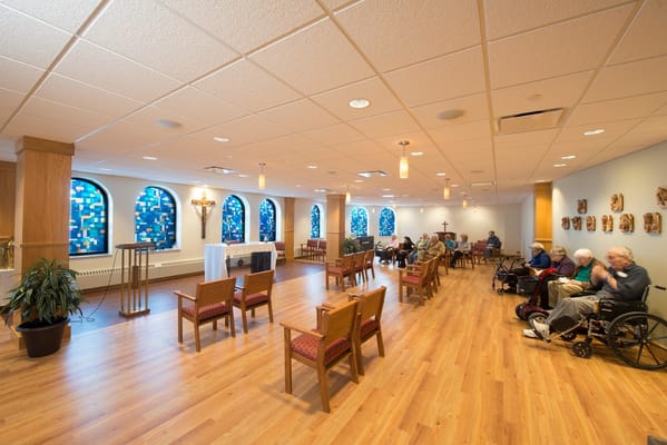 Spacious common area with residents seated, featuring stained glass windows.