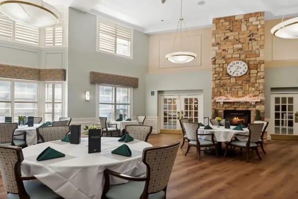 Dining room featuring tables with white tablecloths and a stone fireplace