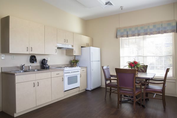 A kitchenette with cabinets, stove, refrigerator, and dining table