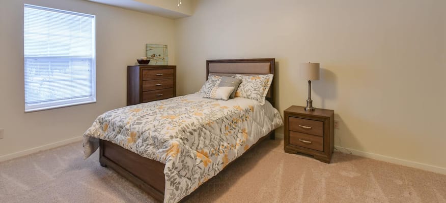 A cozy bedroom featuring a bed, nightstands, and a window.