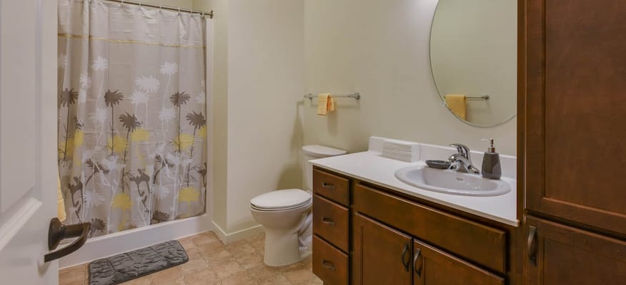 A well-lit bathroom with a shower curtain, sink, and toilet.