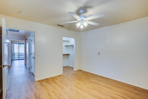Empty resident room with wood flooring and a ceiling fan