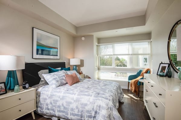 Cozy bedroom featuring a bed, bedside lamps, and large windows.
