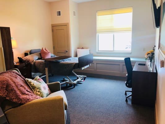 Cozy private room with bed, sitting area, and desk.