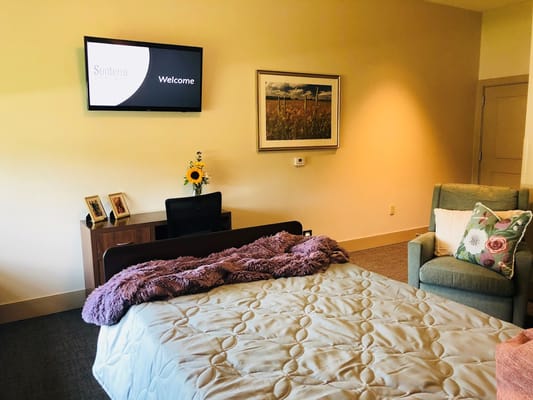 A welcoming bedroom with a bed, chair, and TV display showing 'Welcome' at Sunterra Springs Springfield.