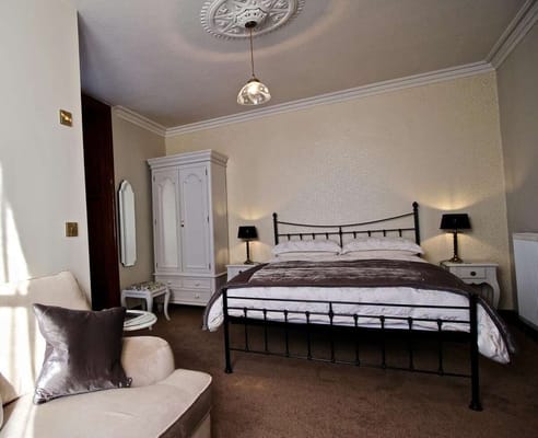 A cozy bedroom featuring a metal frame bed, soft lighting, and elegant decor.
