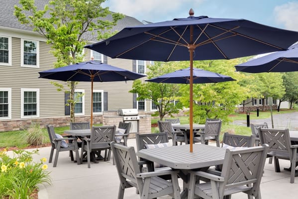 Gray wooden tables and chairs with blue umbrellas in an outdoor seating area