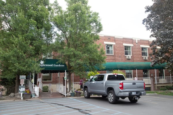 Exterior view of Maplewood Gardens with residents and vehicle