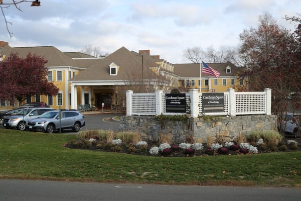 Front entrance of Coachman Square at Woodbridge with landscaping and signage.