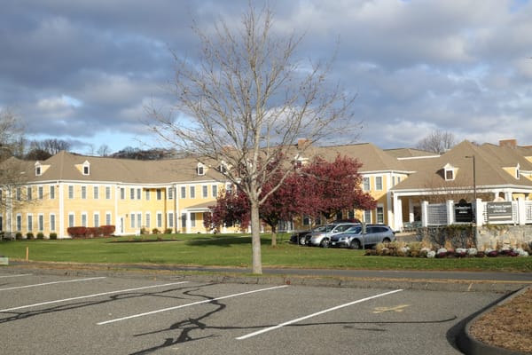 Front view of Coachman Square at Woodbridge with trees and parking space.