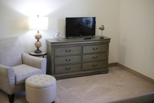 Cozy resident room with a chair, TV, and lamp