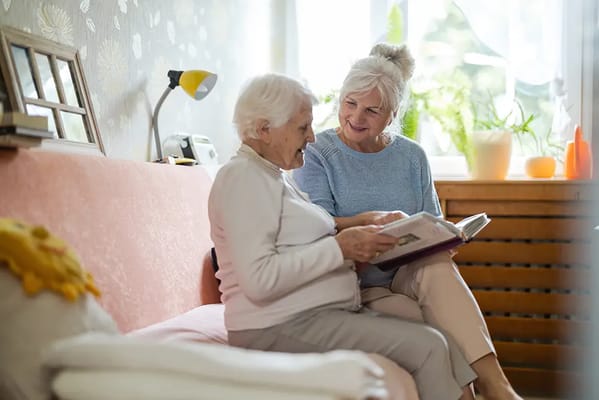 Two seniors enjoying a photo album on a sofa