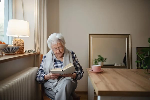 Elderly woman reading a book in a bright room