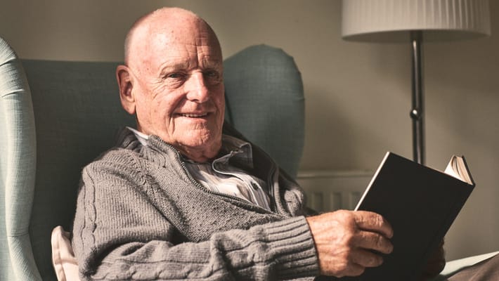Elderly man reading a book in a cozy chair