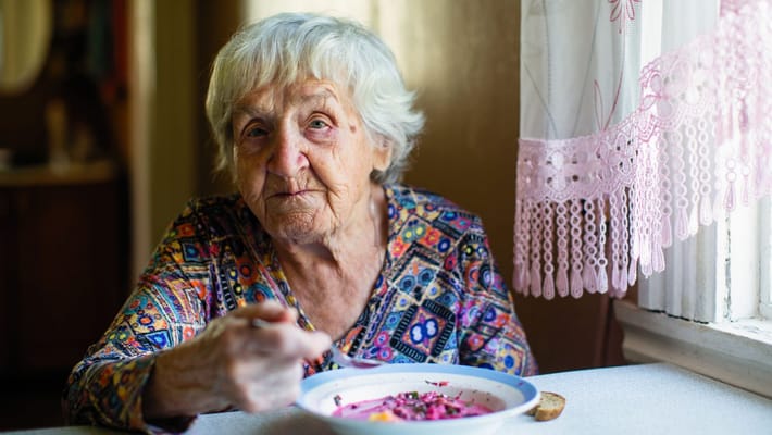 Elderly woman enjoying a meal in a cozy setting