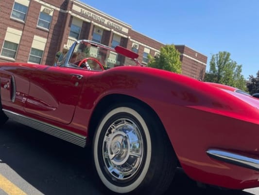 A red classic car parked outside the facility