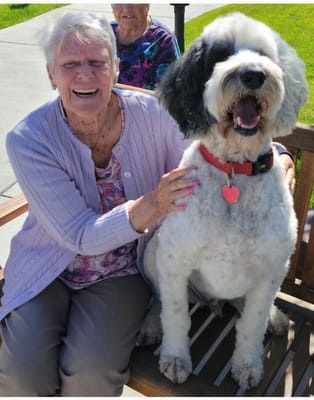 A resident smiling with a dog in an outdoor setting